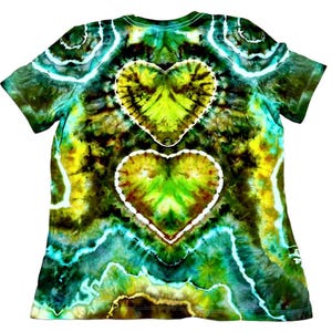 Puede incluir: Una camiseta te&ntilde;ida con un dise&ntilde;o de coraz&oacute;n. La camiseta presenta una vibrante mezcla de colores, incluyendo verde, amarillo y azul. Dos formas de coraz&oacute;n se muestran prominentemente en la parte delantera, delineadas en blanco. El dise&ntilde;o de la camiseta tiene un aspecto psicod&eacute;lico y art&iacute;stico.
