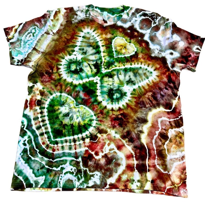 May include: A tie-dye t-shirt with a butterfly and heart design. The shirt features a vibrant mix of colors, including green, brown, red, and white. The butterfly and heart shapes are prominent, with a spiral pattern in the center of the butterfly.