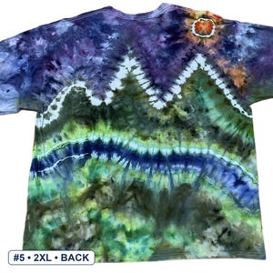 May include: A short-sleeve t-shirt featuring a tie-dye pattern with a mountain landscape design in shades of purple, dark green, lime green, and blue. A white sun-like circle is at the top right. Text at the bottom left reads #5 &bull; 2XL &bull; BACK.