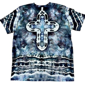 May include: A tie-dye t-shirt with a large white and blue cross design centered on the front. The shirt has a dark blue and gray background with white stripes on the sleeves and bottom hem. The shirt is a crew neck.
