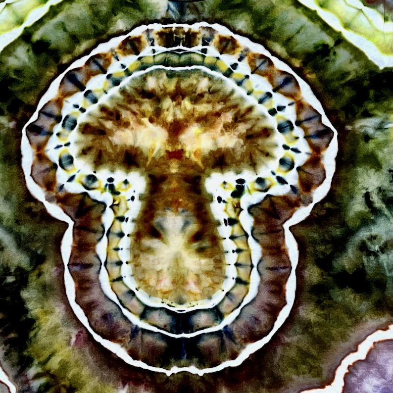 May include: A tie-dye fabric featuring a central mushroom-shaped motif in shades of brown, tan, and yellow, surrounded by concentric rings of white, dark brown, and deep olive green, creating a symmetrical, organic, and layered pattern.