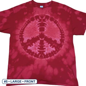 Peut inclure: Un t-shirt &agrave; manches courtes avec un motif tie-dye rouge et rose et un symbole de paix bien visible au centre. Le v&ecirc;tement pr&eacute;sente une encolure ronde et une petite &eacute;tiquette au col. Le texte en bas indique #5 &bull; LARGE &bull; FRONT.