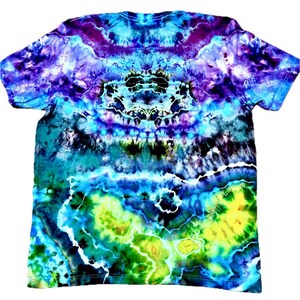 Op de afbeelding: Een T-shirt met korte mouwen en een levendig tie-dye patroon. Het shirt heeft een mix van kleuren, waaronder blauw, paars, groen en geel, wat een uniek en artistiek ontwerp cre&euml;ert. Het tie-dye effect is prominent over het hele kledingstuk.