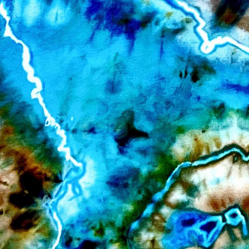 May include: A textile surface featuring a tie-dye pattern with vibrant shades of bright blue, deep turquoise, and dark brown. The design includes distinct white, jagged, lightning-like lines that traverse the fabric, creating a high-contrast effect.