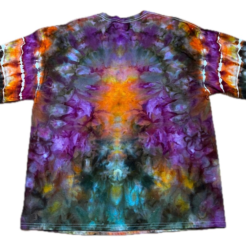May include: A short-sleeve t-shirt featuring a vibrant tie-dye pattern with a symmetrical design. The colors include deep purple, bright orange, dark charcoal, and hints of teal, blending together in a swirling, organic, and kaleidoscopic effect.