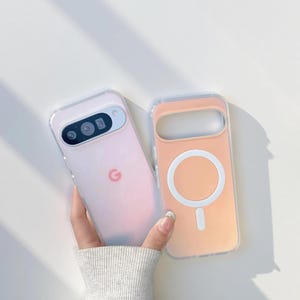 Könnte beinhalten: Zwei Handyhüllen, eine hellrosa und eine pfirsichfarbene, werden gezeigt. Die hellrosa Hülle hat einen Kameraausschnitt und ein Google-Logo. Die pfirsichfarbene Hülle hat einen weißen Kreis und ein Minuszeichen. Beide Hüllen haben transparente Ränder.