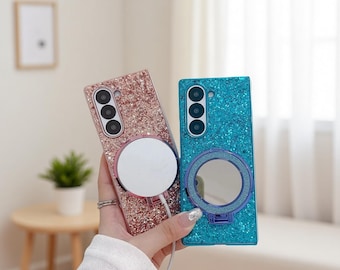 May include: Two sparkly phone cases are displayed, one in rose gold and the other in teal. The rose gold case has a white circular attachment with a charging cable. The teal case features a circular mirror attachment. Both have a triple-lens camera.
