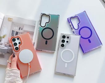 May include: Four clear phone cases in shades of peach, iridescent green, and purple. Each case has a circular magnetic charging pad and a camera cut-out. The cases are designed for a smartphone.