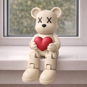 May include: A cream-colored bear figurine with black cross-shaped eyes and a black nose. The bear is holding a red heart. The bear is sitting on a white surface with a window in the background.