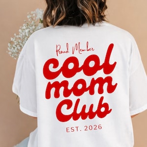 Peut inclure: Un t-shirt blanc avec un texte rouge au dos indiquant Proud Member cool mom Club EST. 2026. Le vêtement présente des manches courtes et un col rond, avec le motif imprimé dans une police cursive audacieuse au centre du dos.