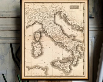 May include: A vintage map of Italy in a brown frame, with the title "ITALY" printed in the top right corner. The map shows the country's regions and major cities, with details of rivers, mountains, and coastlines. The map is printed on aged paper with a cream background and brown ink.