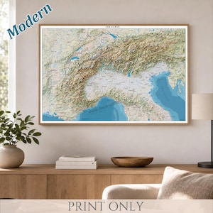 May include: A framed wall map titled LES ALPES featuring a detailed topographic relief of the Alpine mountain range, including surrounding terrain and bodies of water in shades of green, brown, and blue, with the text Modern and Print Only.