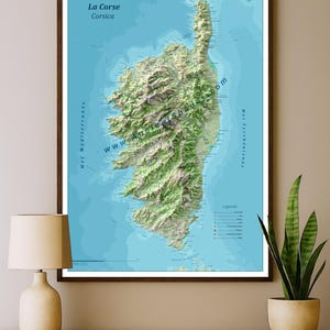 Może przedstawiać: Oprawiona mapa 3D Korsyki, francuskiej wyspy na Morzu Śródziemnym. Mapa przedstawia topografię wyspy w odcieniach zieleni i brązu na niebieskim tle, z tekstem "La Corse Corsica".