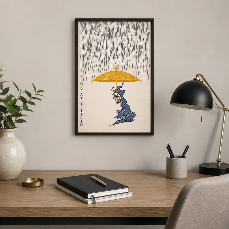 May include: A framed wall art print featuring a dark blue map of Great Britain held by a hand under a large yellow umbrella. The background shows vertical gray lines representing rain, with the text GREAT BRITAIN printed vertically in black.