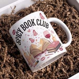 Può includere: Una tazza di ceramica bianca con manico nero e la scritta "But First, Coffee" in nero, in grassetto. La tazza è su una superficie bianca. La tazza è alta circa 10 cm.