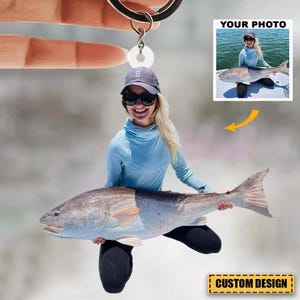 May include: A personalized keychain featuring a photo of a person holding a large fish. The keychain has a circular charm with a photo of a person holding a fish, with the words "YOUR PHOTO" and "CUSTOM DESIGN" visible.