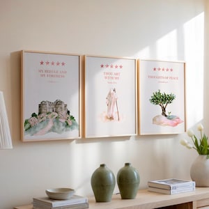 Puede incluir: Tres láminas de arte mural enmarcadas con ilustraciones en acuarela y texto. La lámina izquierda muestra una fortaleza de piedra con el texto 'MY REFUGE AND MY FORTRESS'. La central muestra una figura con un bastón y 'THOU ART WITH ME'. La derecha muestra un árbol y 'THOUGHTS OF PEACE'.