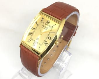 Reloj de pulsera Seiko SQ Quartz Barrel Tank vintage: esfera romana dorada, correa de piel color canela