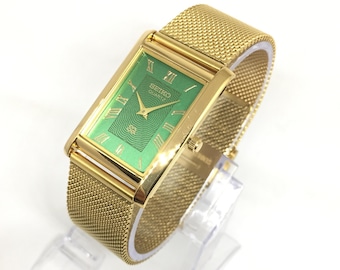 Reloj de pulsera Seiko SQ Quartz Tank vintage: esfera romana, correa de acero inoxidable, verde y dorado.