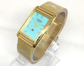 Reloj de pulsera vintage Seiko SQ Quartz Tank: esfera romana, correa de acero inoxidable, Tiffany y dorado.