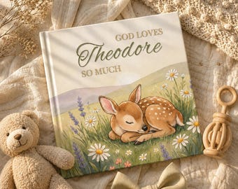 Könnte beinhalten: Ein quadratisches Hardcover-Buch mit cremefarbenem Einband, das ein schlafendes Rehkitz auf einem Feld mit Gänseblümchen und Lavendel zeigt. Der Text auf dem Einband lautet GOD LOVES Theodore SO MUCH in einer Mischung aus Serif- und Schreibschrift.