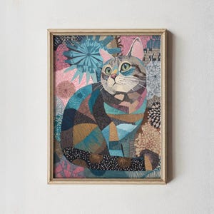 Può includere: Opera d'arte incorniciata raffigurante un'illustrazione stilizzata di un gatto. Il gatto è raffigurato con un design patchwork nei toni del blu, marrone e rosa. Lo sfondo presenta un motivo floreale in colori simili, il tutto all'interno di una cornice di legno chiaro.