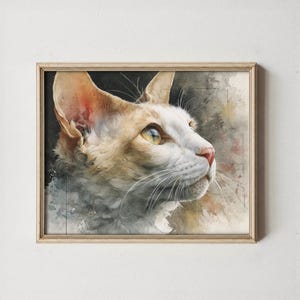 May include: Watercolor painting of a cat in a wooden frame. The cat has white and tan fur, with yellow eyes and long whiskers. The background features muted watercolor washes of gray, black, and beige.