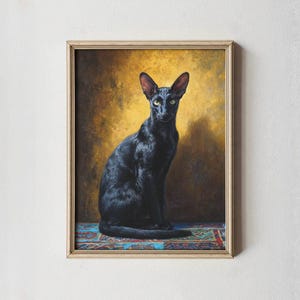 Op de afbeelding: Een ingelijst schilderij van een slanke zwarte kat met grote oren en gele ogen, tegen een goudbruine achtergrond. De kat zit rechtop op een patroonkleed met blauwe, rode en groene accenten. Het kunstwerk zit in een houten lijst.