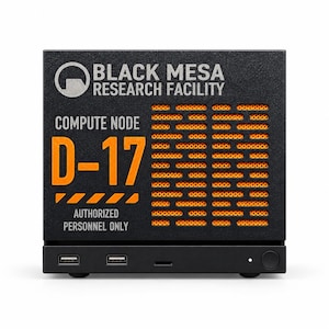 Könnte beinhalten: Ein schwarzes, quadratisches Computergehäuse mit dem Text Black Mesa Research Facility, Compute Node D-17 und Authorized Personnel Only. Die Frontplatte enthält ein orangefarbenes Lüftungsgitter, zwei USB-Anschlüsse und einen runden Netzschalter.