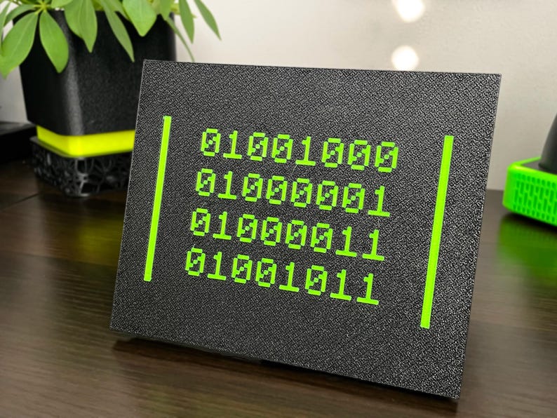 Angled view of four green binary rows on a textured black plaque.