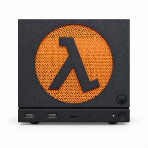May include: A square black computer case featuring a large circular orange mesh speaker grille on the front panel. A black Greek lambda symbol is centred over the orange mesh. The base includes two USB ports, a small power button, and a status light.