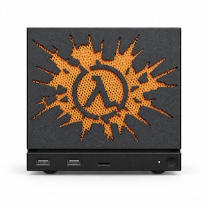 Puede incluir: Un dispositivo electrónico rectangular negro con un panel frontal texturizado que presenta un recorte del símbolo Lambda rodeado por un patrón de estallido irregular, revelando un interior de malla naranja brillante. La base incluye dos puertos USB.