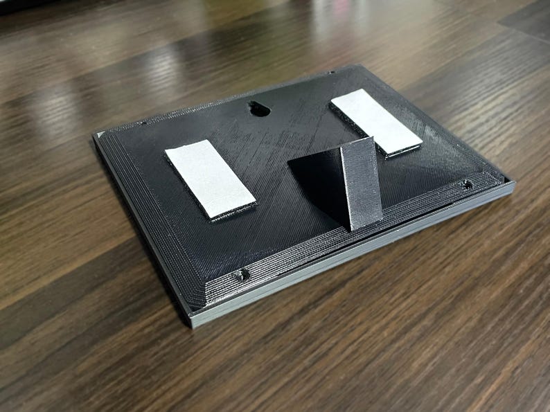 Rear of the plaque with desk stand, keyhole and adhesive mounting strips.