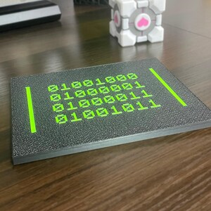 Low side angle showing the raised neon-green binary artwork and plaque thickness.