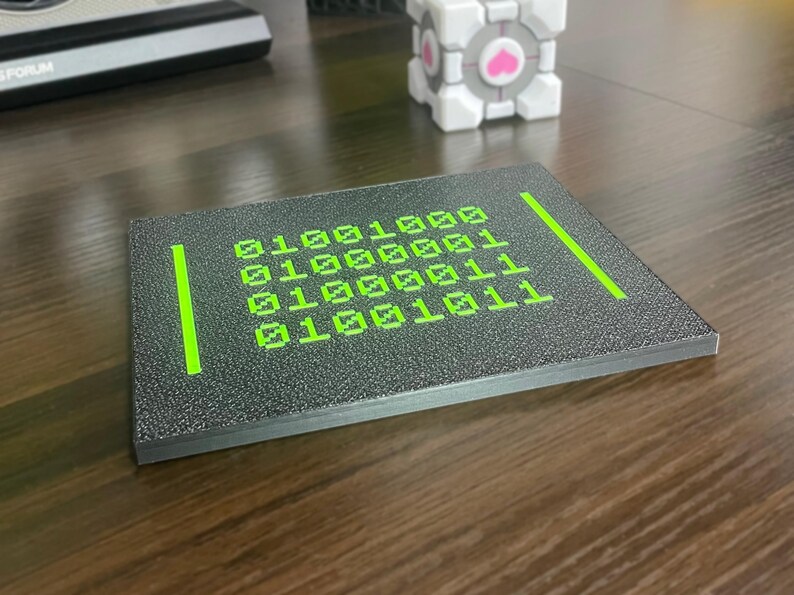 Low side angle showing the raised neon-green binary artwork and plaque thickness.