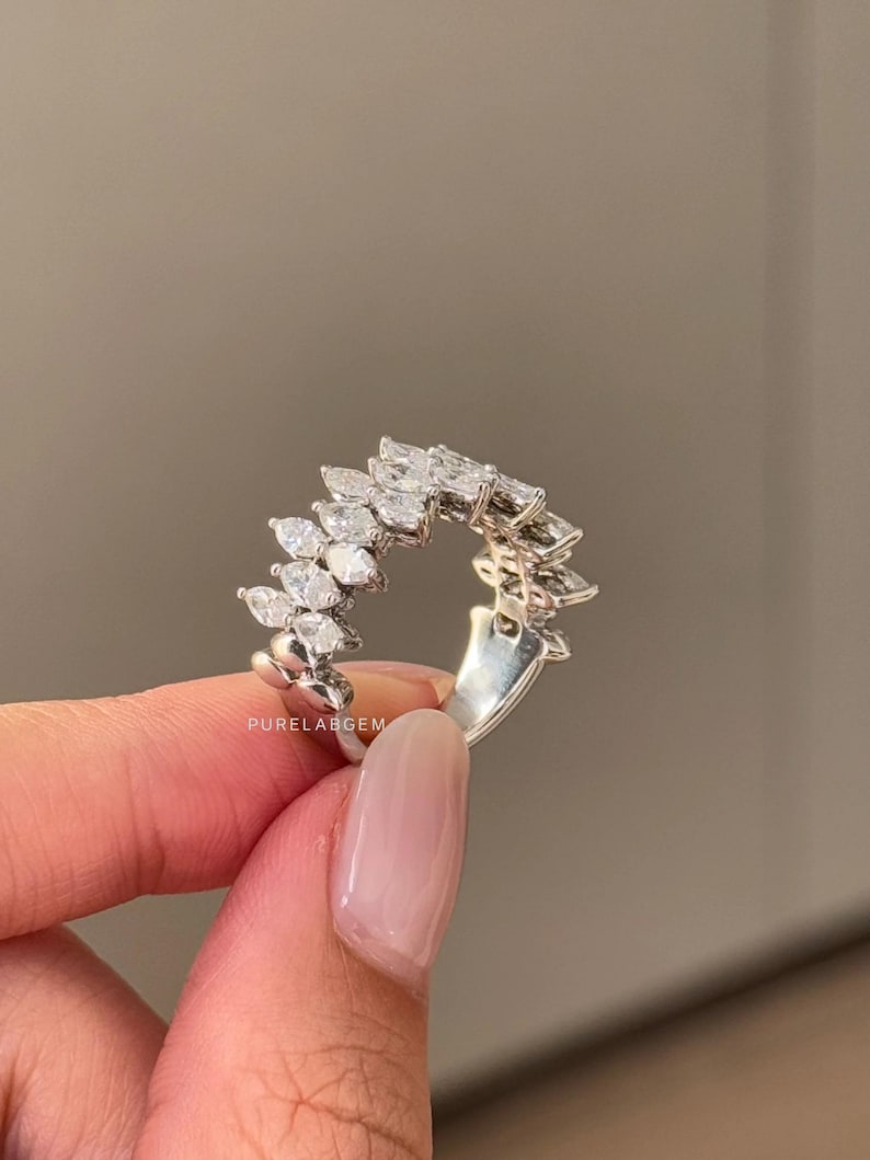 Pode incluir: Anel de prata com uma s&eacute;rie de pedras preciosas transparentes com corte marquesa dispostas em um padr&atilde;o curvo. O anel tem uma banda de prata. O texto "PURELABGEM" &eacute; vis&iacute;vel no anel.