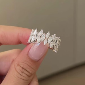 Pode incluir: Um anel de ouro branco com uma dupla fileira de diamantes em corte marquise. Os diamantes s&atilde;o colocados pr&oacute;ximos uns dos outros, criando uma faixa cont&iacute;nua e brilhante. O anel &eacute; exibido em um fundo neutro.