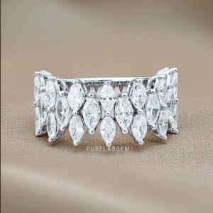Pode incluir: Um anel de prata com uma s&eacute;rie de pedras preciosas com corte marquesa. O anel apresenta um design sim&eacute;trico com as pedras preciosas dispostas em um padr&atilde;o repetitivo. O texto "PURELABGEM" &eacute; vis&iacute;vel no anel.