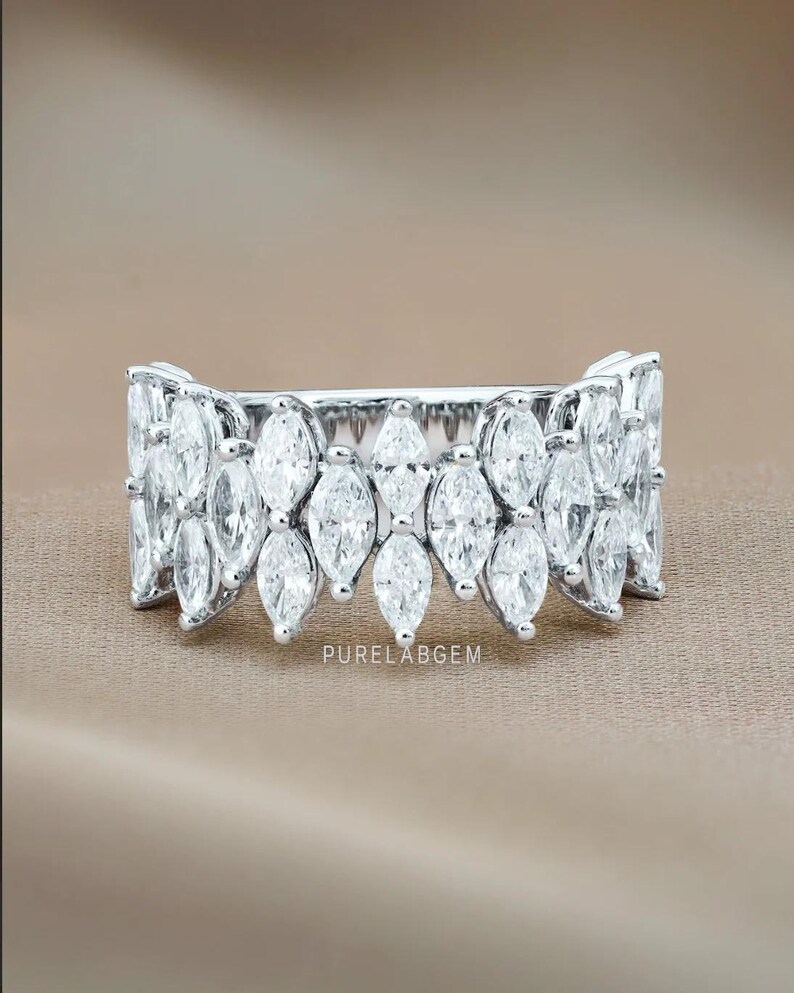 Pode incluir: Um anel de prata com uma s&eacute;rie de pedras preciosas com corte marquesa. O anel apresenta um design sim&eacute;trico com as pedras preciosas dispostas em um padr&atilde;o repetitivo. O texto "PURELABGEM" &eacute; vis&iacute;vel no anel.