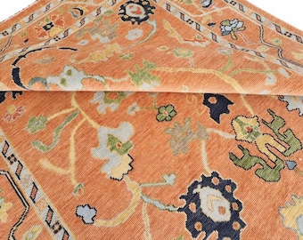 May include: Close-up of a folded orange rug with a detailed floral pattern. The rug features a mix of colors, including blue, green, yellow, and white, creating a vibrant and intricate design. The rug's texture and pattern are clearly visible.