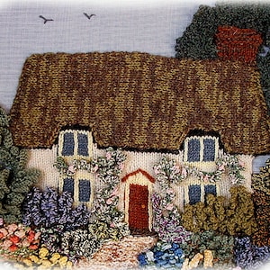 May include: A knitted cottage scene with a thatched roof, white walls, and blue window frames. The cottage is surrounded by colorful knitted flowers and bushes. Two birds fly in the light blue sky.