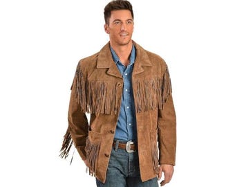 May include: A brown suede jacket with long fringe detailing across the chest, shoulders, and sleeves. The jacket has a button-up front, two front pockets, and a notched collar. The model is wearing a blue button-down shirt and jeans.