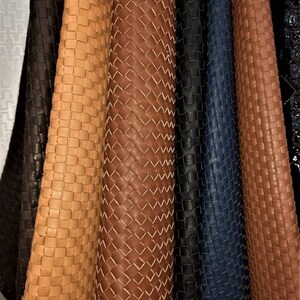 May include: A collection of vertical fabric strips featuring a woven basket-weave pattern. The strips are displayed in a variety of colours including dark brown, light tan, medium brown, black, and deep navy blue, arranged side by side.