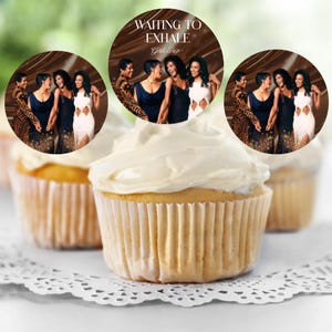 Op de afbeelding: Cupcakes met witte frosting en eetbare toppers met de tekst "WAITING TO EXHALE Girls Trip" en een afbeelding van vijf vrouwen in avondkleding. De cupcakes staan op een wit kanten kleedje.