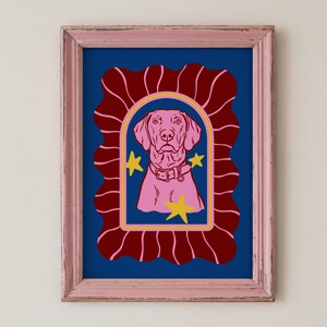May include: Pink framed art print featuring a pink dog illustration within a yellow arched frame, set against a dark blue background. The dog wears a collar and is flanked by yellow star accents. The frame is a distressed pink.