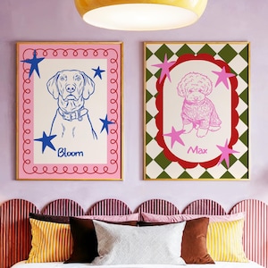 May include: Two framed dog portraits. One features a blue line drawing of a dog named Bloom, surrounded by blue stars and a pink border. The other shows a pink poodle named Max, set against a green and white checkered background with pink stars.