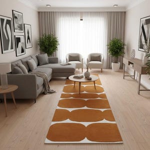 A long, mustard yellow and white geometric runner rug with wavy shapes on a light wood floor in a living room with a gray sectional sofa.
