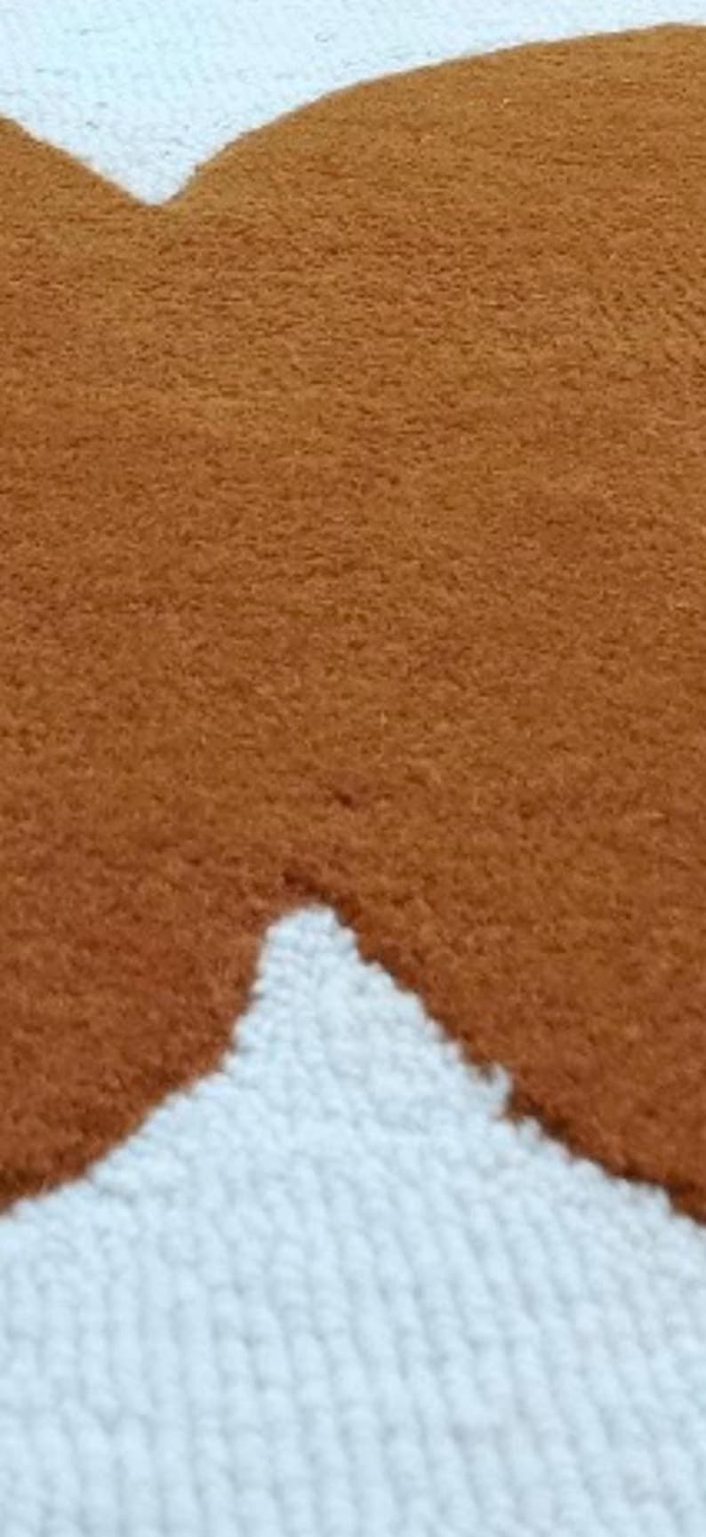 A very close-up, textured view of the mustard yellow and white wavy geometric pattern of the rug.