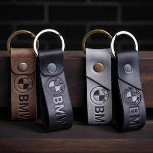 Puede incluir: Cuatro llaveros de cuero en marrón, negro y gris, cada uno con el logotipo de BMW y el nombre BMW en relieve en la correa. Los llaveros tienen anillas metálicas y cierres de botón a presión.