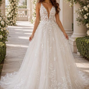 May include: A floor-length ivory gown featuring a deep V-neckline and thin straps. The bodice and skirt are adorned with intricate white floral lace appliques that cascade down into a full, layered tulle skirt with a sweeping train.